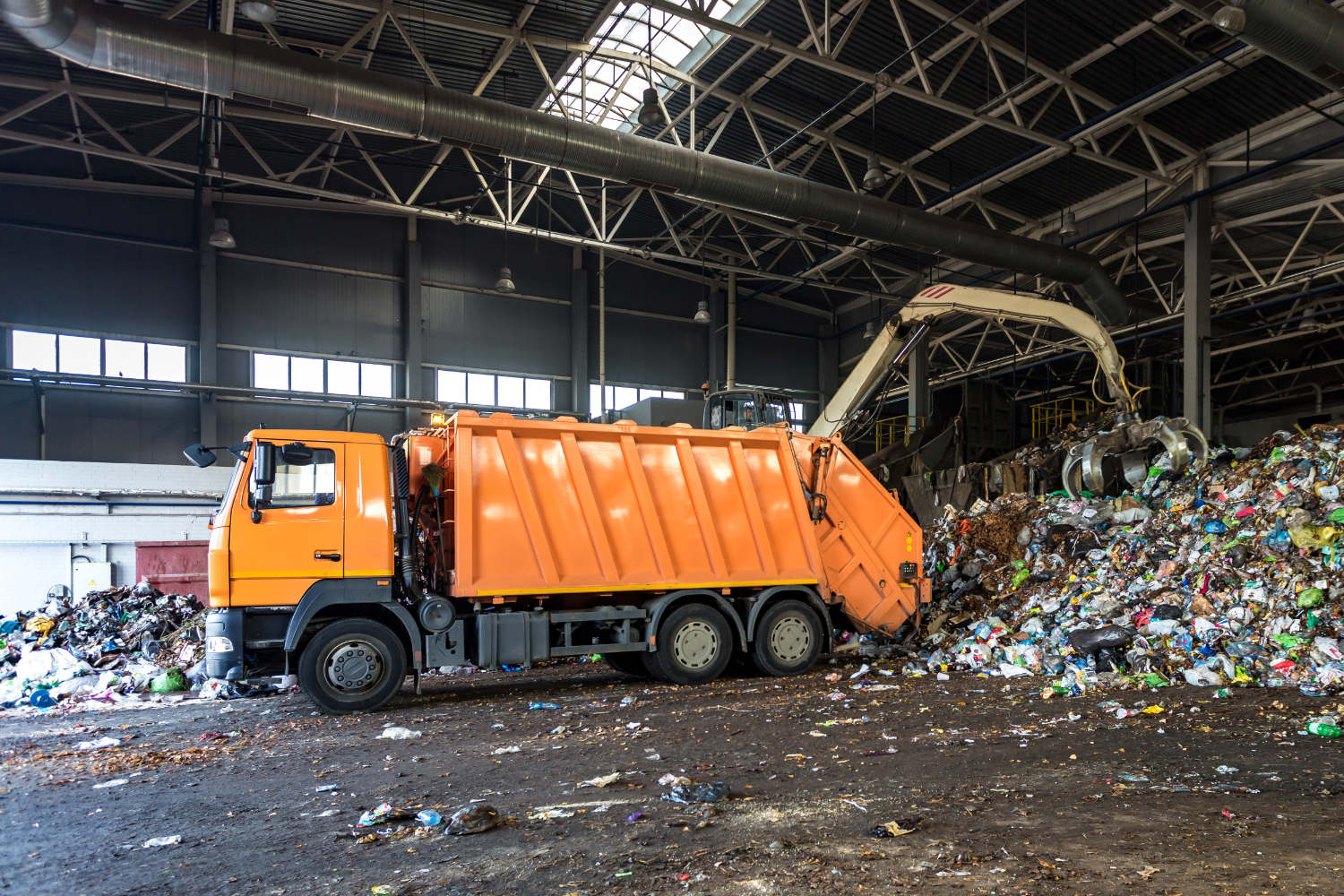 Orange truck throwing garbage onto recycling site